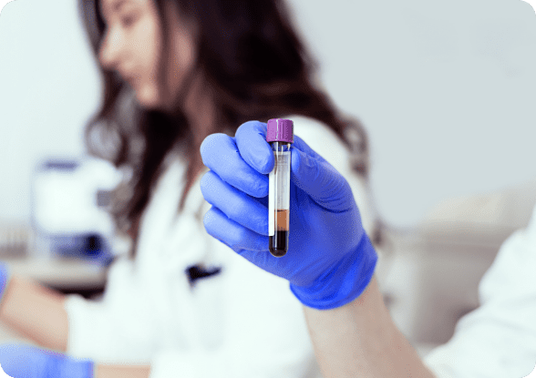 gloved hand holding a test tube with blood